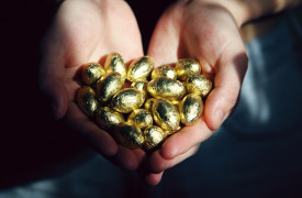 Two hands holding golden chocolate Easter eggs