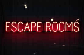 Tekst in neon, rood op zwart, met de letters escape rooms