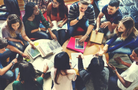 Groep studenten rondom een tafel met laptops en notitieblokken