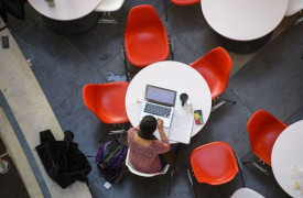 Student achter laptop alleen aan een tafel