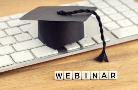 Afstudeerhoed op een toetsenbord, met daarvoor rechtopstaande blokjes met daarop de letters 'Webinar'