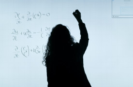 Een vrouw schrijft wiskundige vergelijkingen op een bord