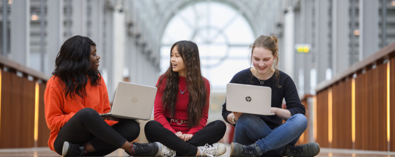 Drie studenten zitten op de grond