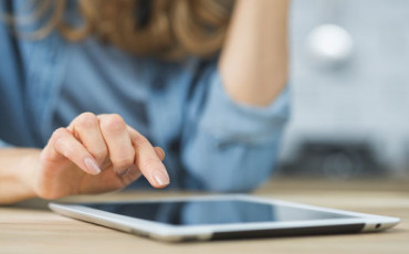 Een vrouw wijst met haar hand iets aan op een tablet