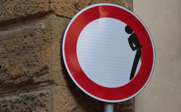 een verbodsbord waarin een poppetjes om het hoekje kijkt