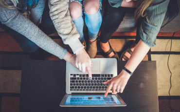 Meerdere studenten wijzen naar scherm van 1 laptop