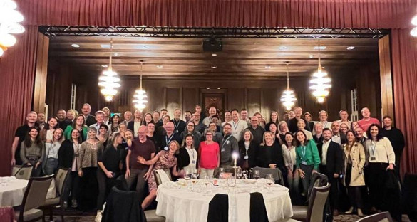 100 mensen staan op een groepsfoto in een restaurant. 