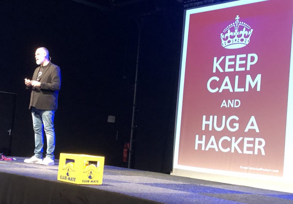 Edwin van Andel met achter hem een foto met de tekst 'Keep calm and hug a hacker'