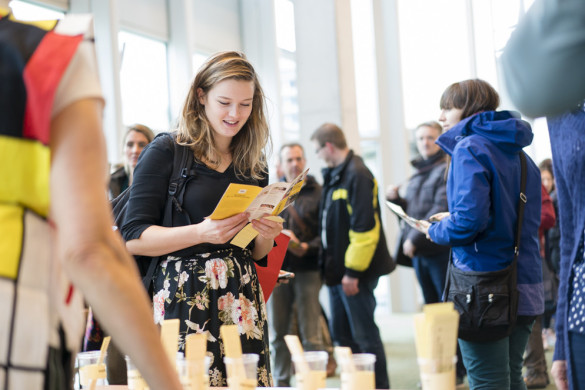 Mensen op het herfstfestival met een jonge vrouw op de voorgrond die een brochure leest