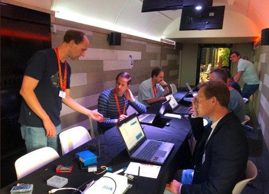 Foto van mensen achter laptops, zittend aan een lange tafel