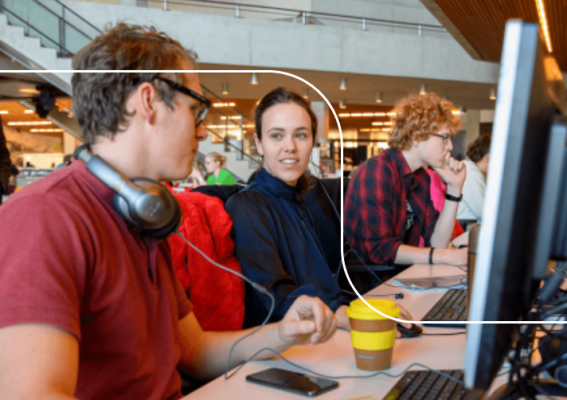 Twee studenten achter de computer praten in de bibliotheek