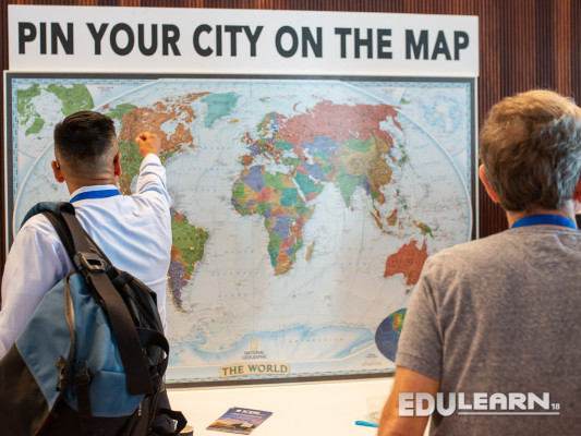 Twee mensen voor een wereldkaart met de tekst 'pin your city on the map'