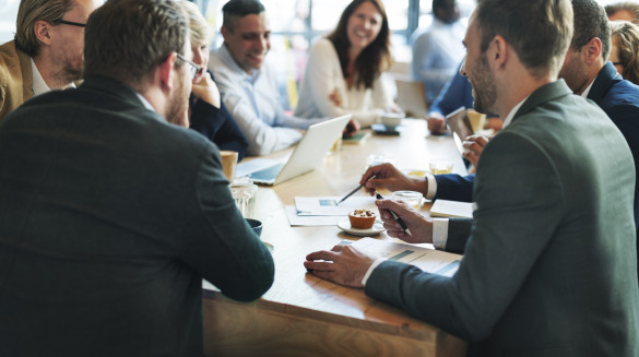 Twee personen in gesprek aan een tafel met documenten en laptops, terwijl ze ideeën uitwisselen tijdens een interactieve sessie over inclusief onderwijs.