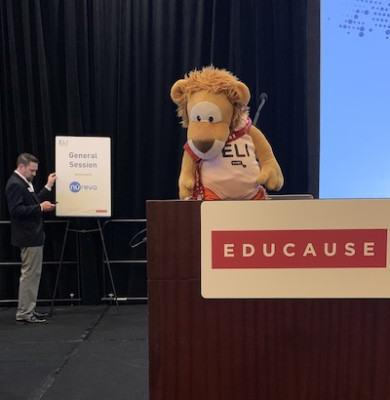 Leeuwenknuffel in een ELI pakje aan de sprekerstafel van Educause