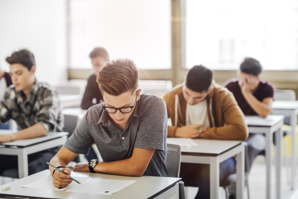 Studenten maken aan afzonderlijke tafels een toets