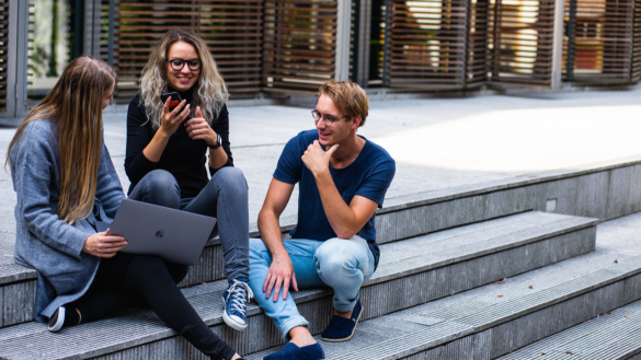 drie studenten zitten buiten op een trap te praten