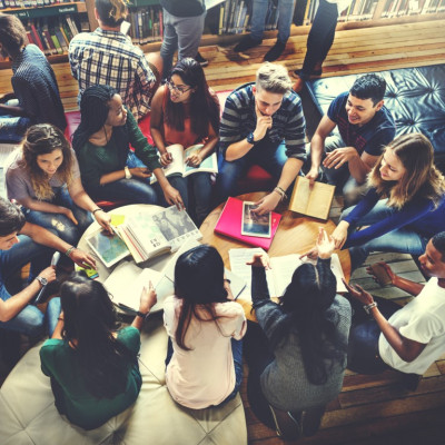 Groep studenten rondom een tafel met laptops en notitieblokken