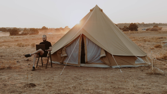 Man achter laptop bij tent