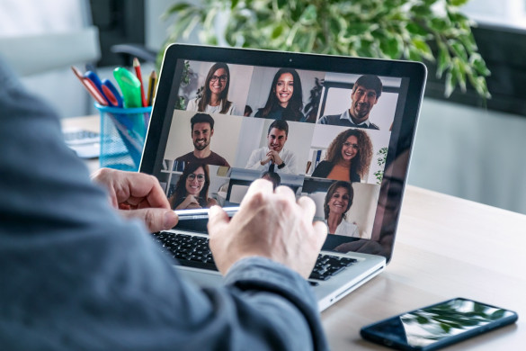 man achter laptop die een online meeting volgt