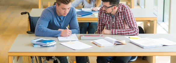 student in een rolstoel en leraar aan tafel in leslokaal