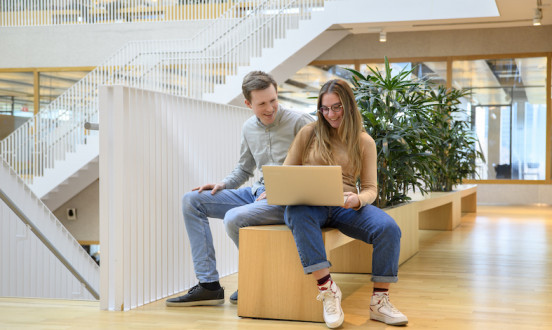 Studenten op een bankje met een laptop op schoot