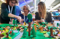 Drie mensen bouwen tijdens de SURF Onderwijsdagen met LEGO aan de Campus van de Toekomst