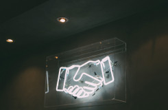 een neonbord van twee handen die elkaar de hand geven