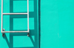 een foto van een ladder tegen een mintgroene muur; de ladder komt niet tot op de grond dus je moet een stukje zelf klimmen