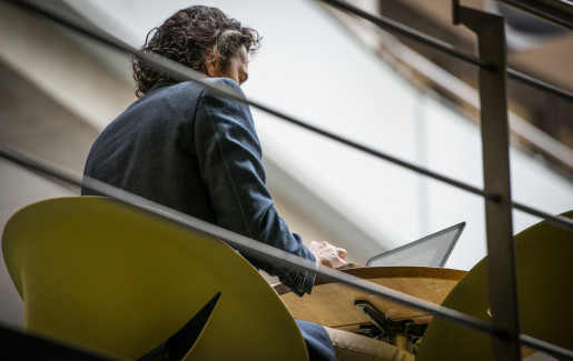 Man achter computer aan tafel op verhoging, foto van verdieping lager genomen