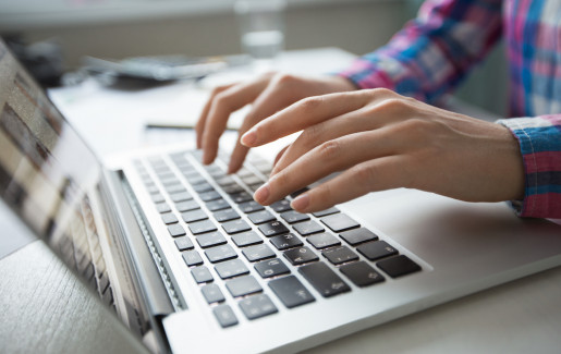 Close-up van handen die op een laptop typen